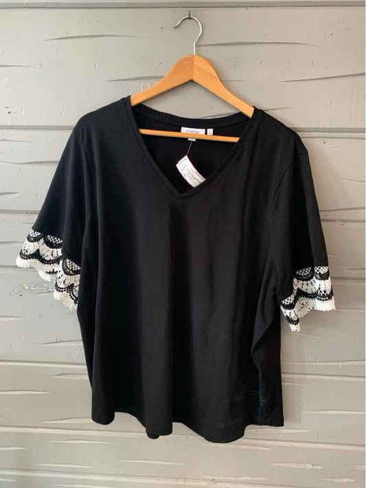 Black V-neck blouse with scalloped white lace sleeves hanging on wooden hanger.
