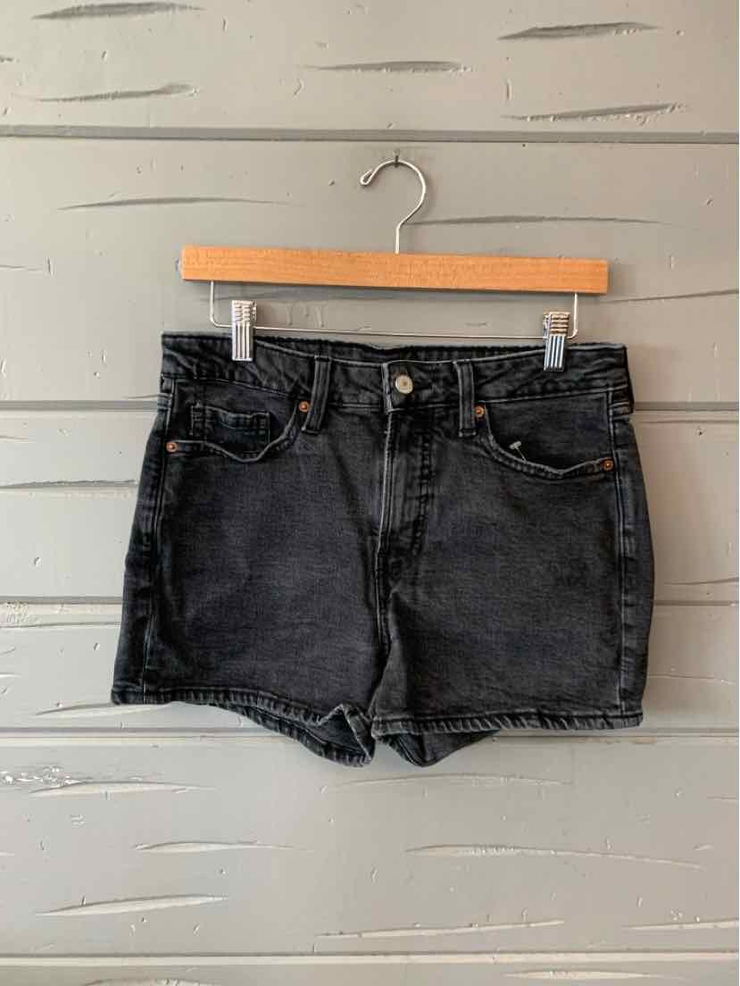 Black denim shorts size 8 with front pockets and belt loops hanging on wooden hanger.