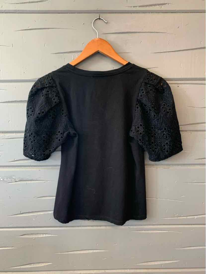 Black short-sleeve top with textured puff sleeves and a round neckline on wooden hanger.