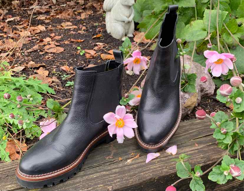 Black leather ankle boots with rounded toes, elastic side panels, and brown stacked soles.