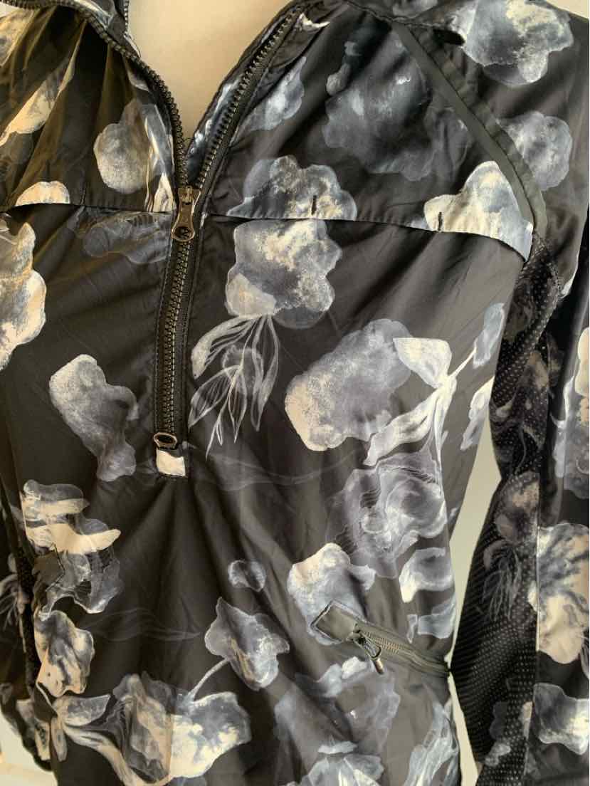 Black quarter-zip jacket with gray and white floral pattern, fitted silhouette, and long sleeves.