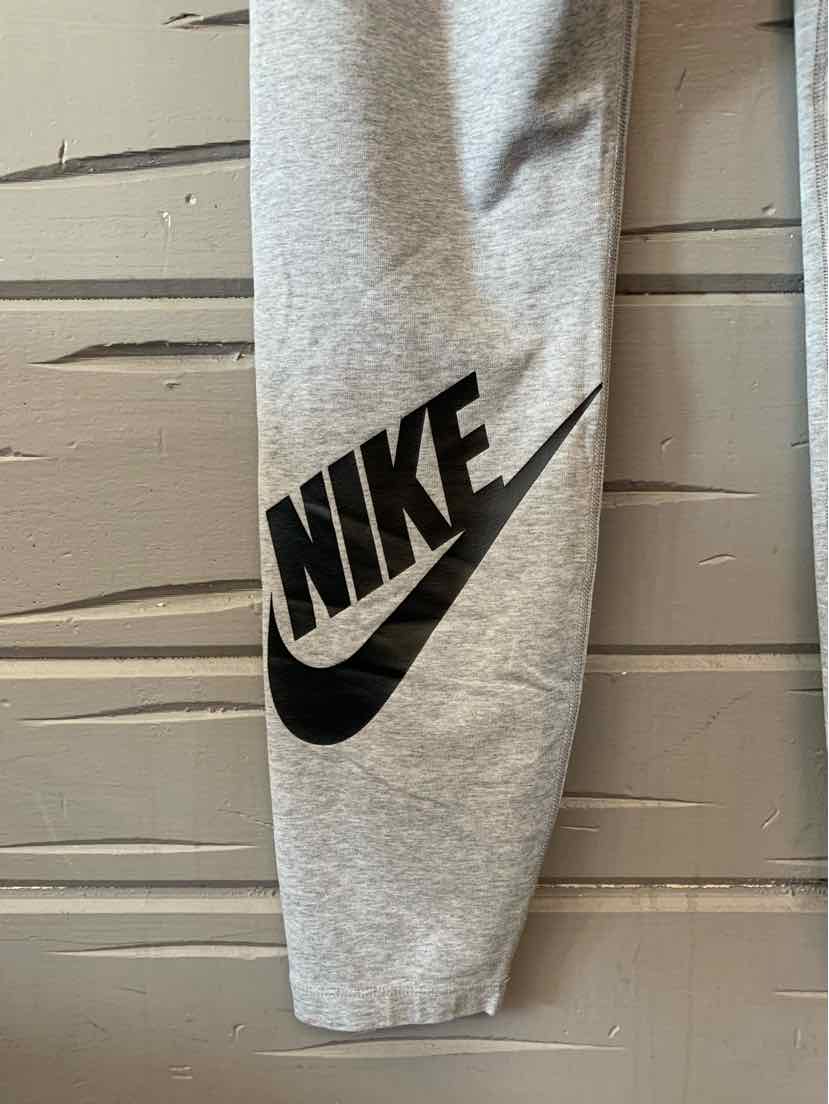 Light gray sweatpants leg with large black Nike logo and swoosh on the lower calf.