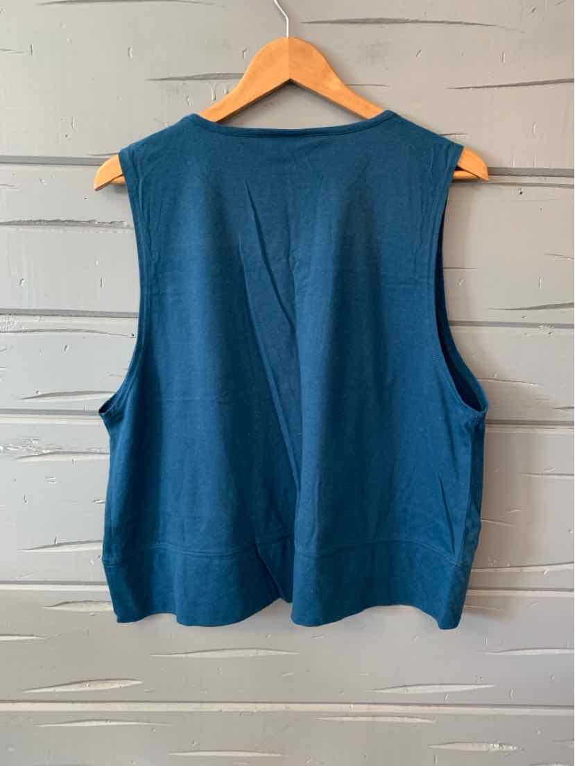 Teal sleeveless cotton tank top with wide armholes and relaxed fit, hanging on wooden hanger.