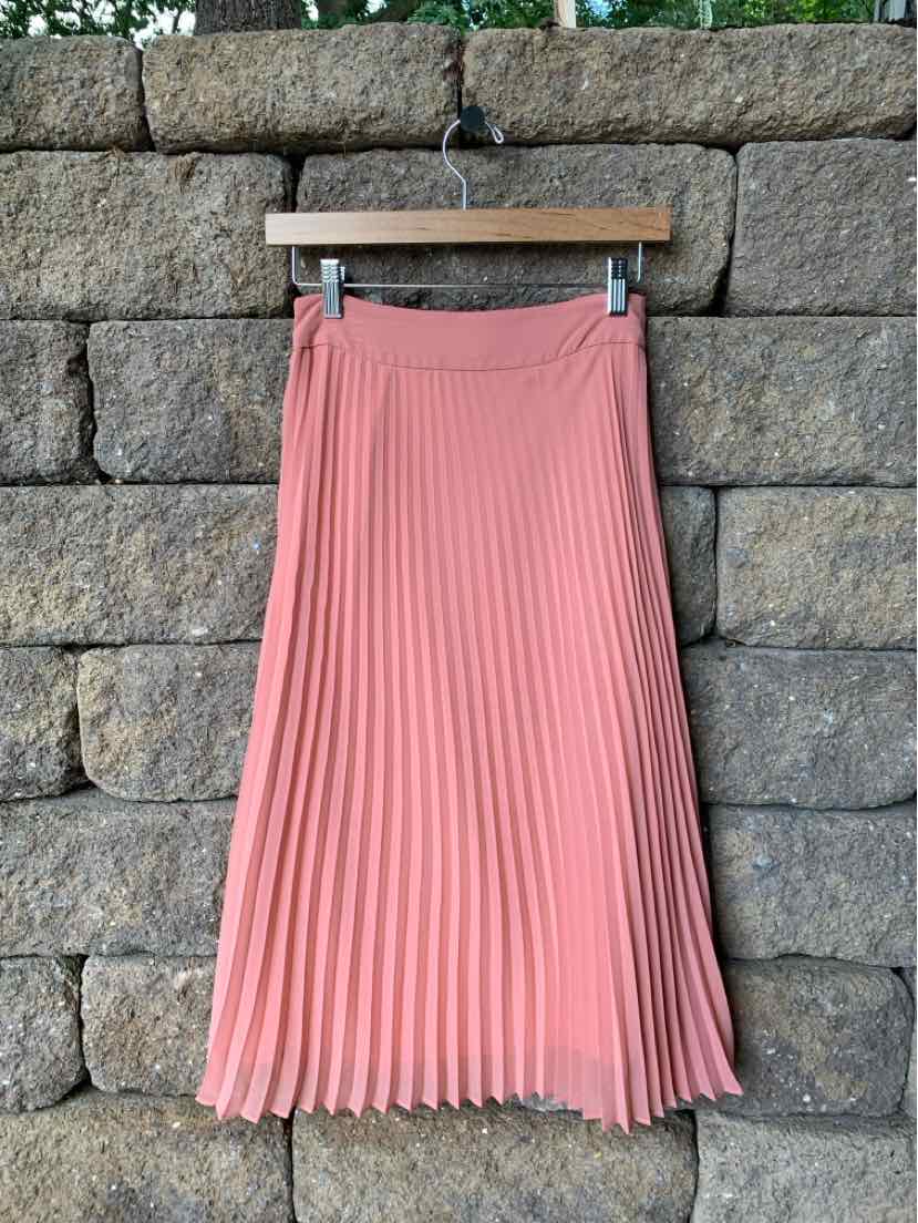 Dusty pink pleated midi skirt with a high waist and flowy fabric hanging on wooden hanger.