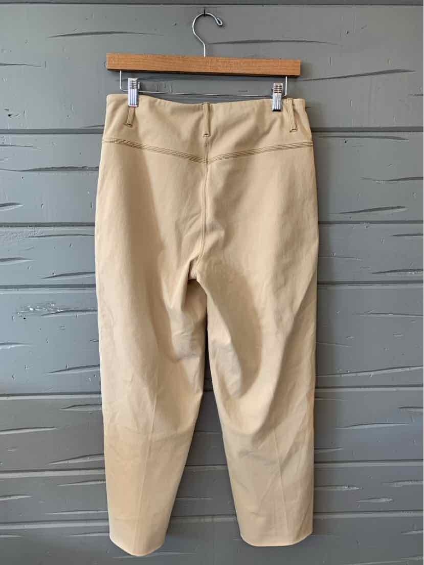 Tan high-waist tapered pants with belt loops, made from smooth fabric, hanging on wooden hanger.