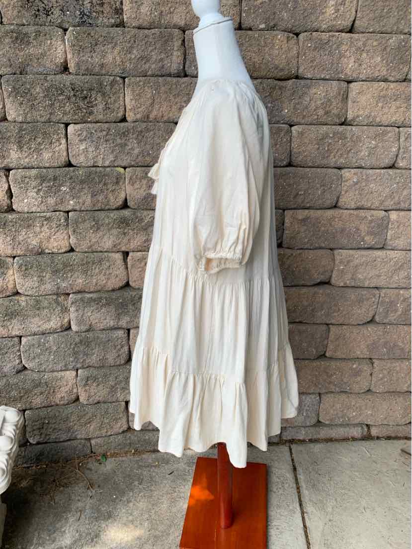 White knee-length dress with 3/4 puff sleeves and tiered ruffle hem made of lightweight fabric.