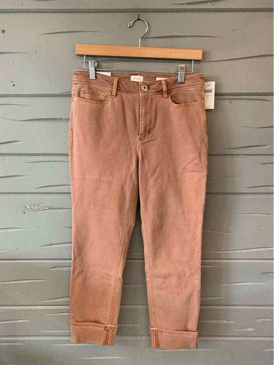 Light brown denim jeans with a slim fit and cuffed hems, size 4, hanging on a wooden hanger.