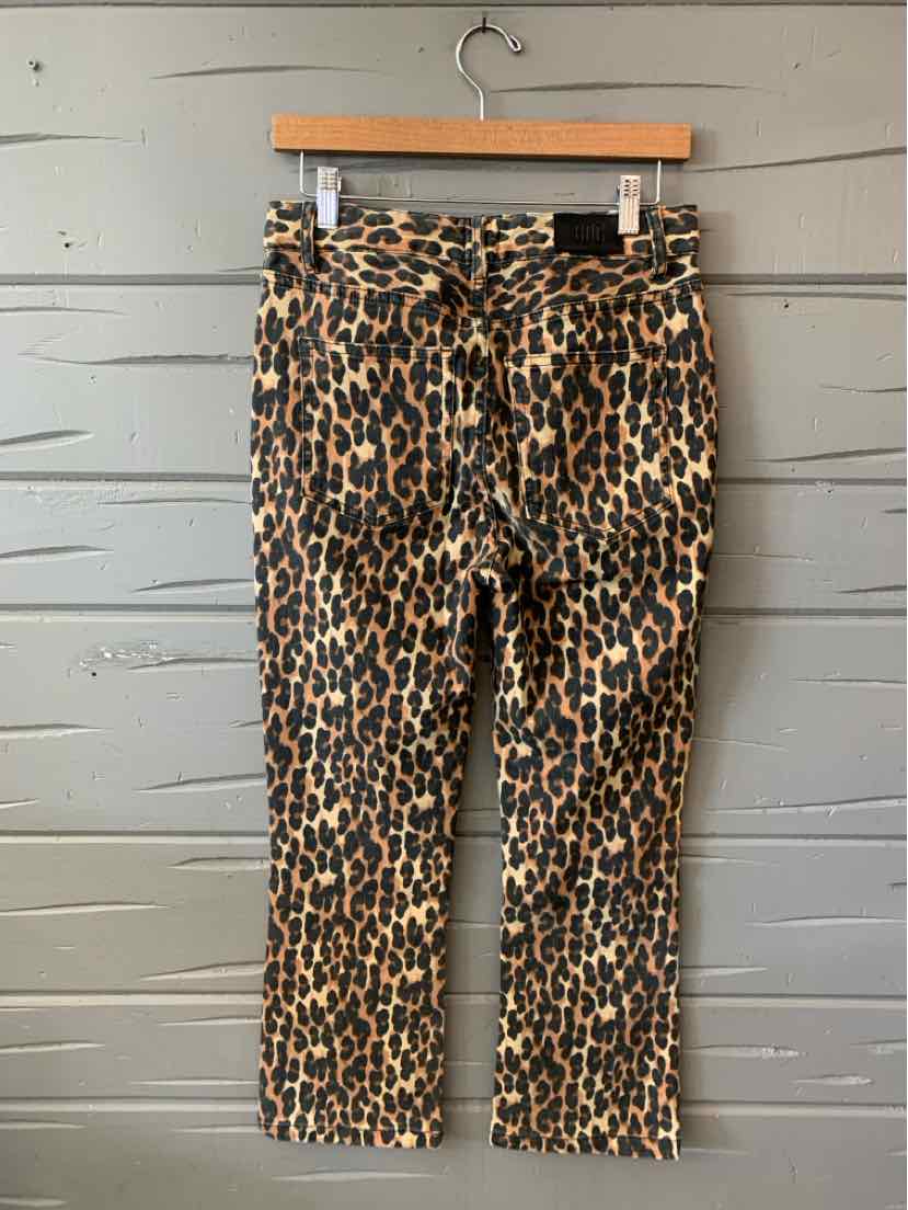 Tan high-waisted jeans with a cheetah print pattern and straight-leg cut hanging on wooden hanger.
