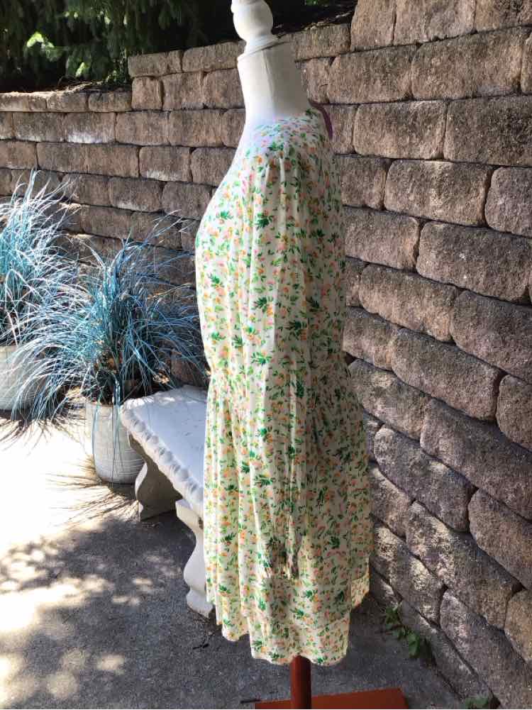 White floral knee-length dress with long sleeves and flowy skirt on mannequin outdoors.