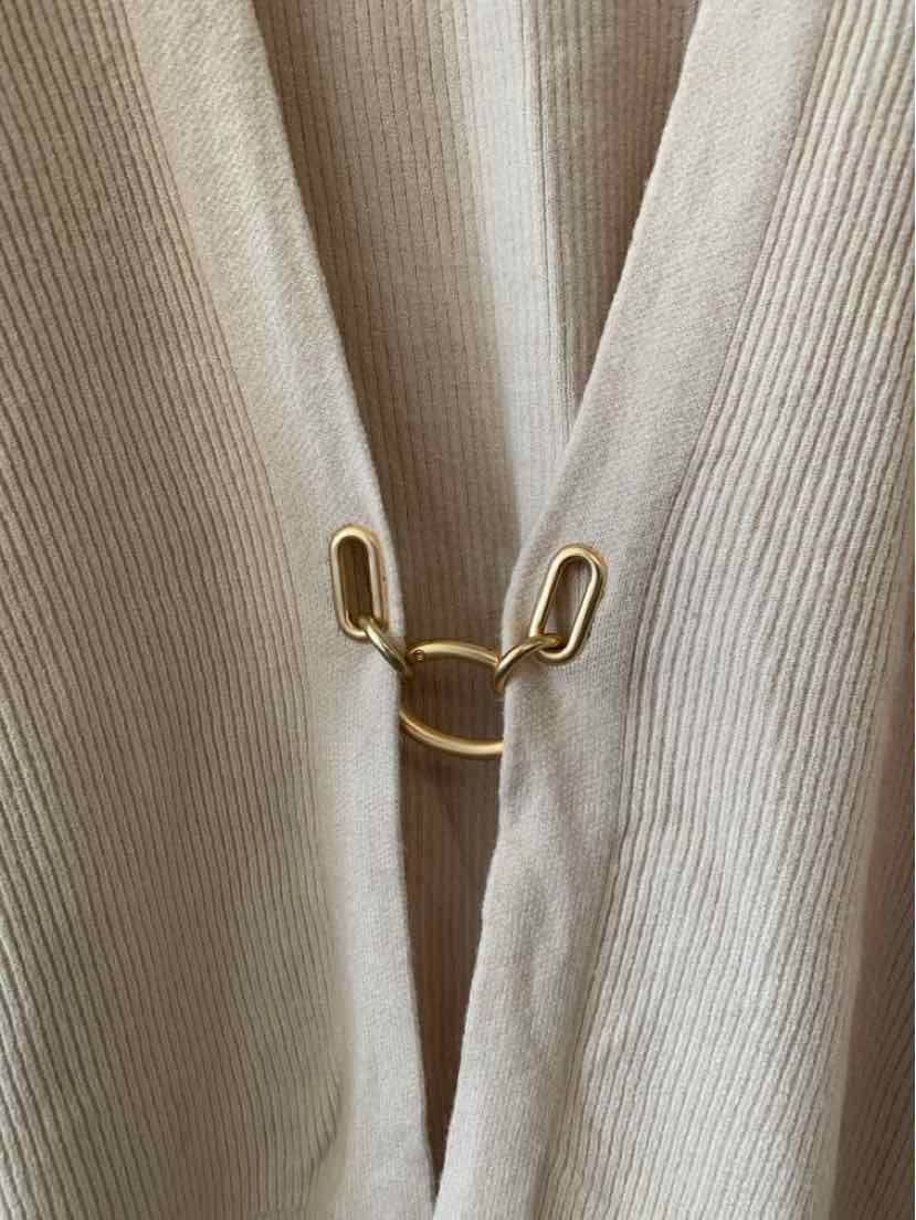 Beige ribbed fabric panels gathered with a small gold-tone metal clip.
