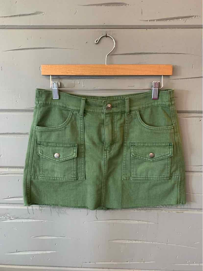 Green mini skirt with front patch pockets and button details, made of solid fabric.