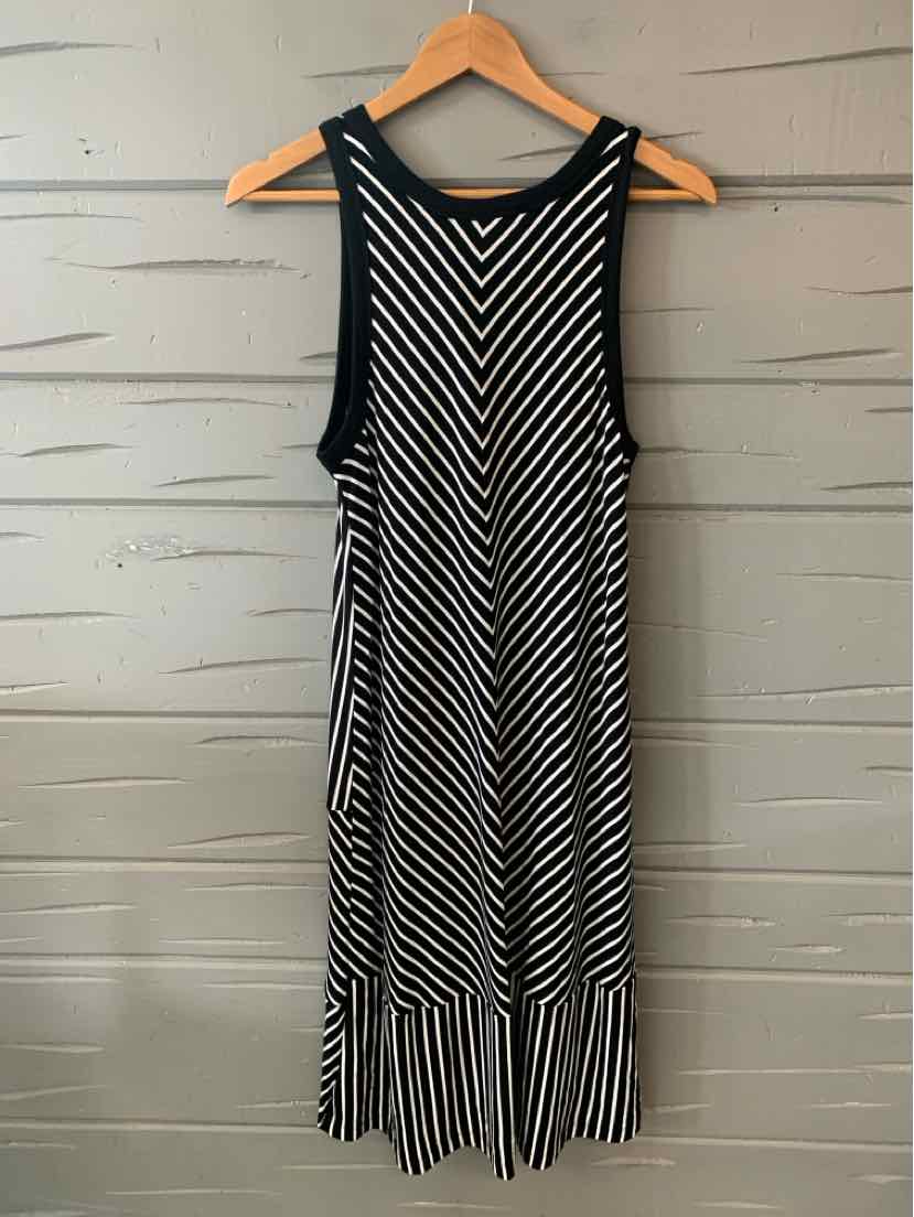 Black and white sleeveless midi dress with vertical and diagonal stripe pattern and ruffled hem.