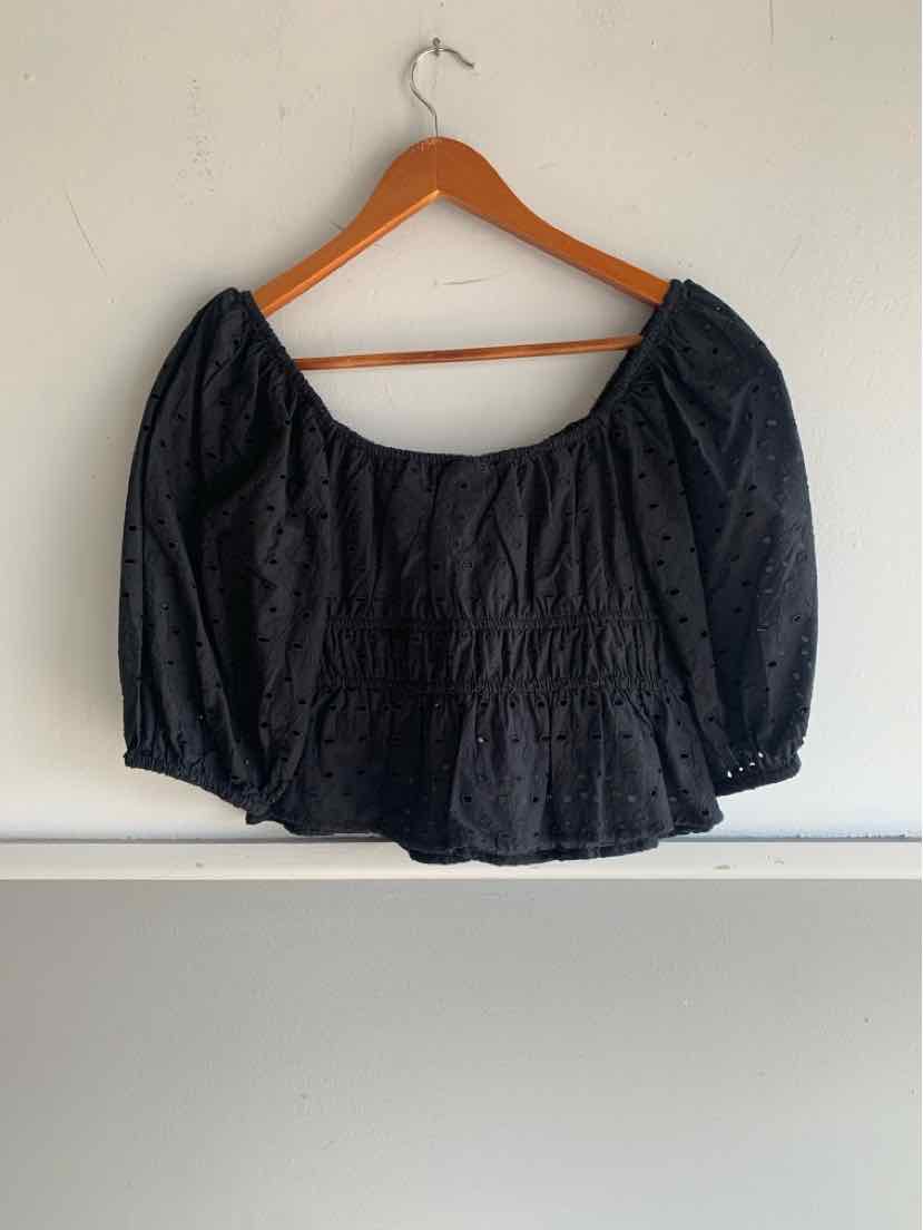 Black eyelet blouse with puffed three-quarter sleeves and square neckline on wooden hanger.