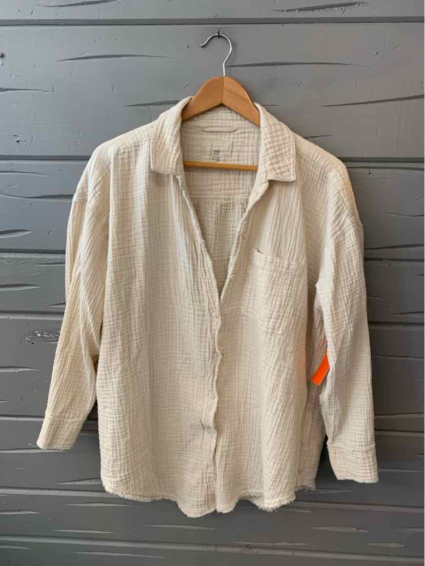 Cream-colored long-sleeve textured button-up shirt with collar and single chest pocket on wooden hanger.