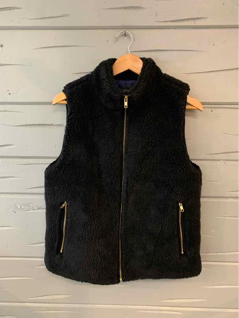Black sherpa fleece vest with high collar, gold zipper, and zippered side pockets on wooden hanger.