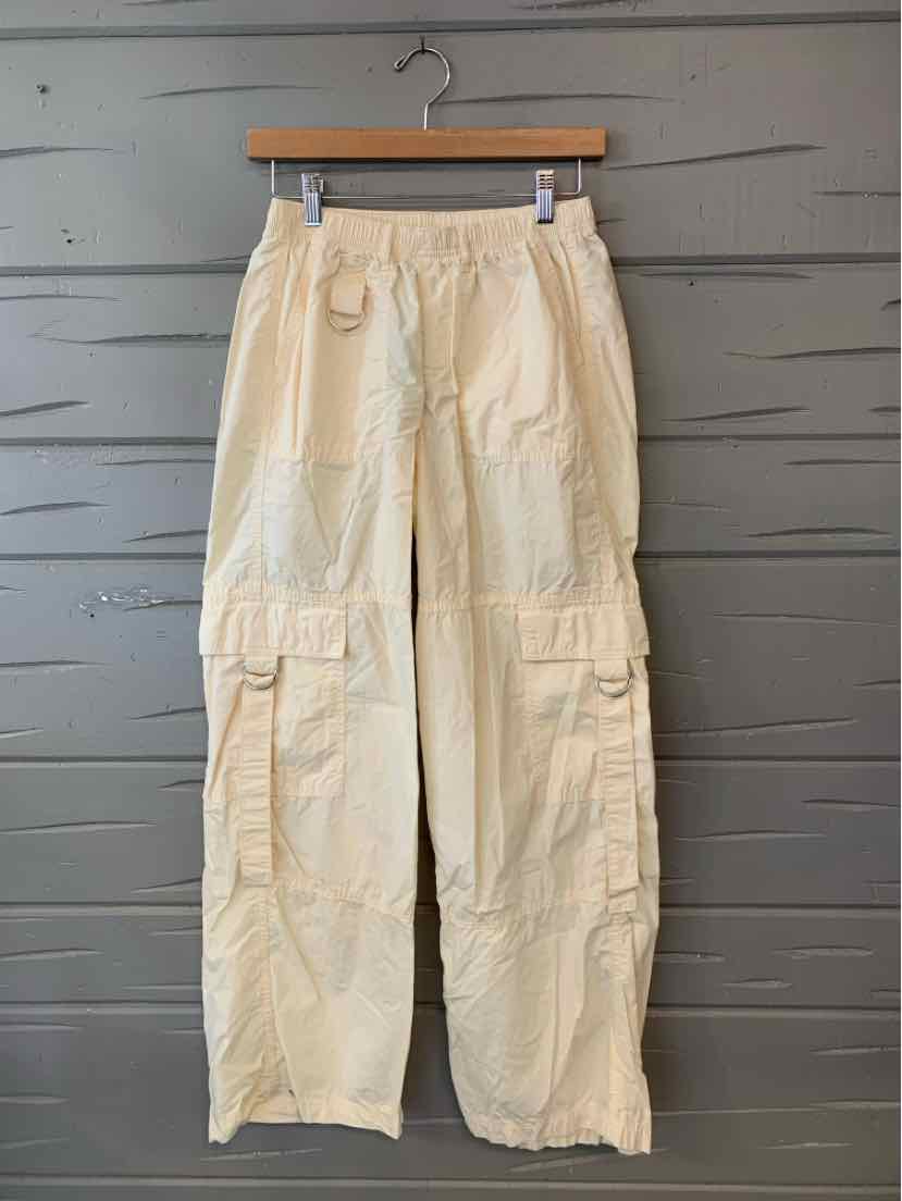 Light beige cargo pants with elastic waistband and multiple front and side pockets, straight leg design.