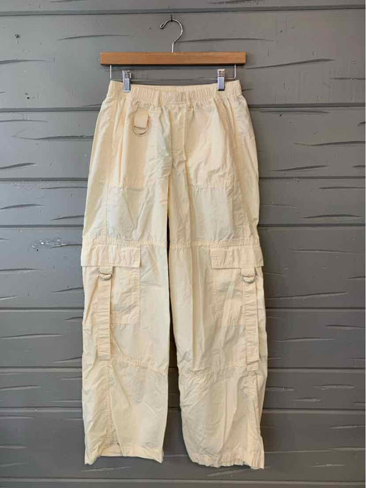 Light beige cargo pants with elastic waistband and multiple front and side pockets, straight leg design.