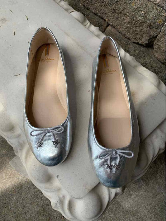 Metallic silver ballet flats with rounded toes, small bows, and smooth leather finish, size 9.5.