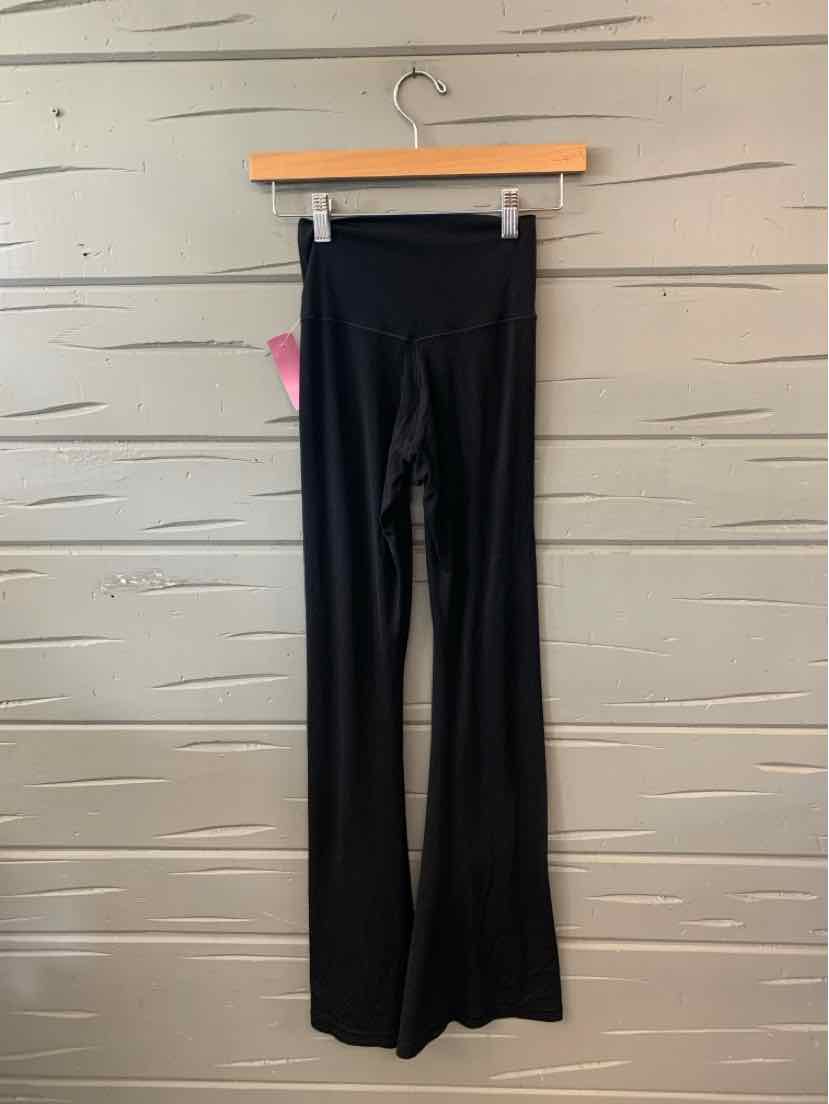 Black high-waist flared leggings with a smooth, solid fabric hanging on a wooden hanger.