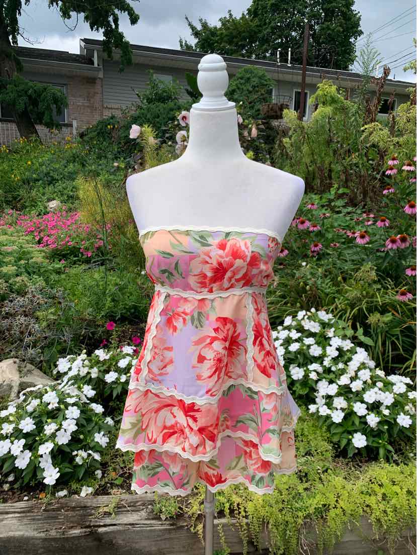 Strapless floral mini dress with layered ruffles in pink, red, and green on light background.