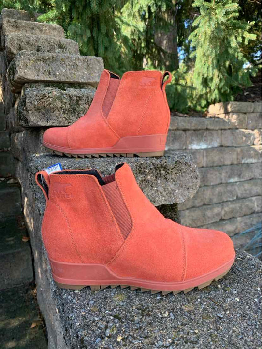 Rust-orange suede ankle boots with rounded toes, elastic side panels, and low rubber soles.