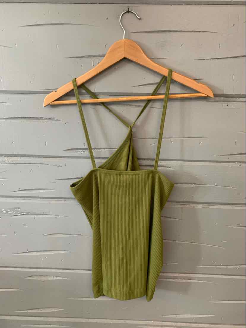 Olive green sleeveless top with crisscross thin straps hanging on wooden hanger against gray wooden wall.
