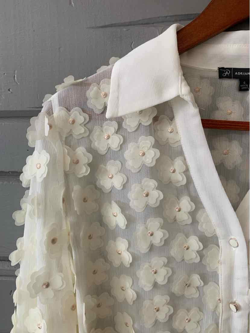 Sheer white blouse with 3D floral appliqués, white collar, and button-down front.