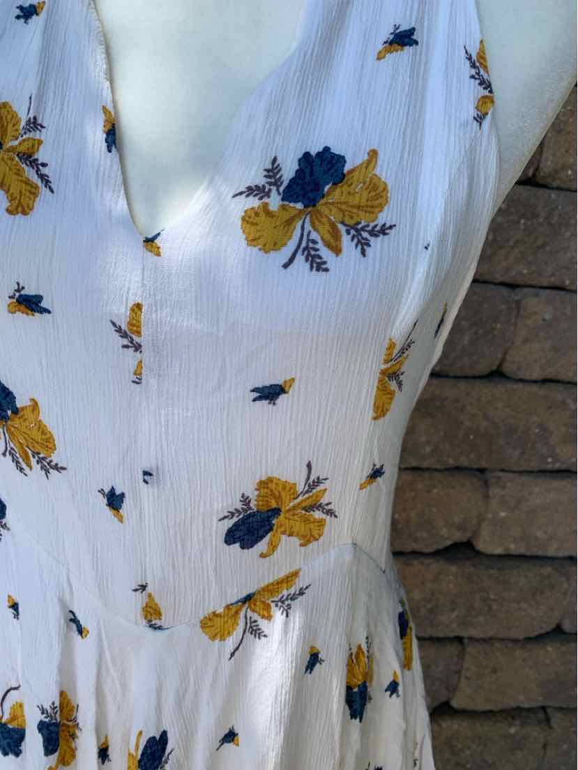 White sleeveless dress with yellow and navy floral print, V-neckline, and gathered waist.