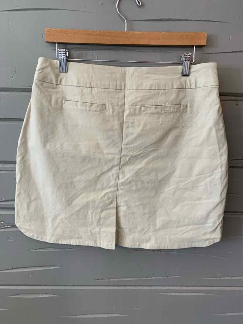 Tan fabric mini skirt with a straight cut and a back center slit hanging on a wooden hanger.