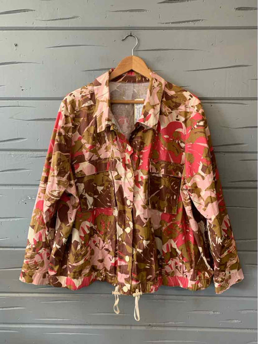 Pink and brown camouflage jacket with drawstring hem and long sleeves hanging on wooden hanger.