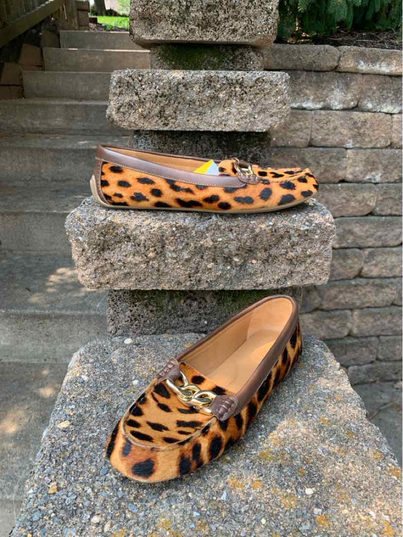 Tan and black cheetah print flat shoe with a rounded toe and gold buckle detail.