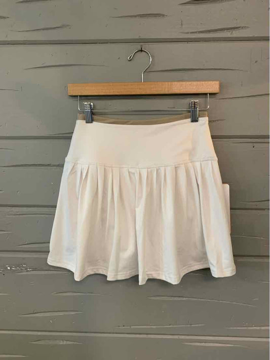 Beige high-waist skirt with a wide waistband and soft pleated flare in lightweight fabric.