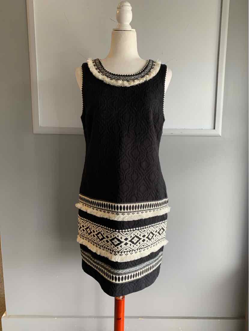 Black sleeveless dress with white embroidered floral and geometric patterns on neckline and hem, fitted silhouette.