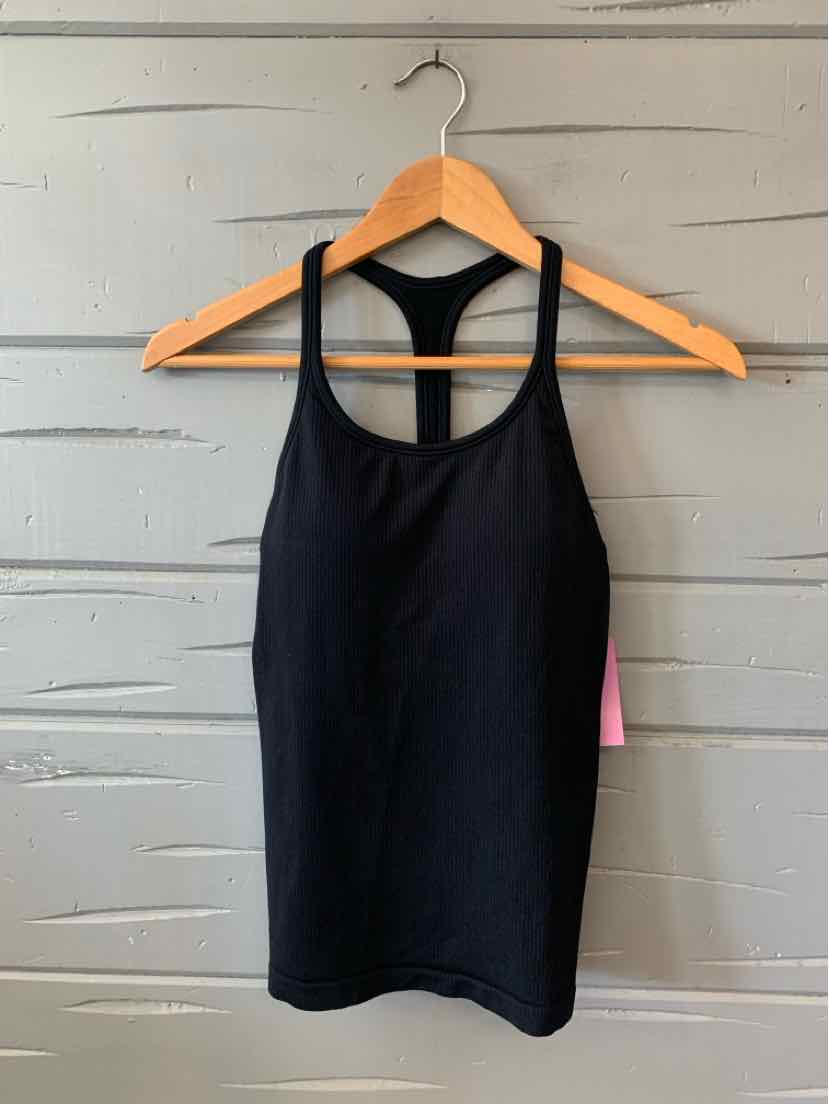Black fitted athletic tank top with racerback design on wooden hanger against gray wooden background.