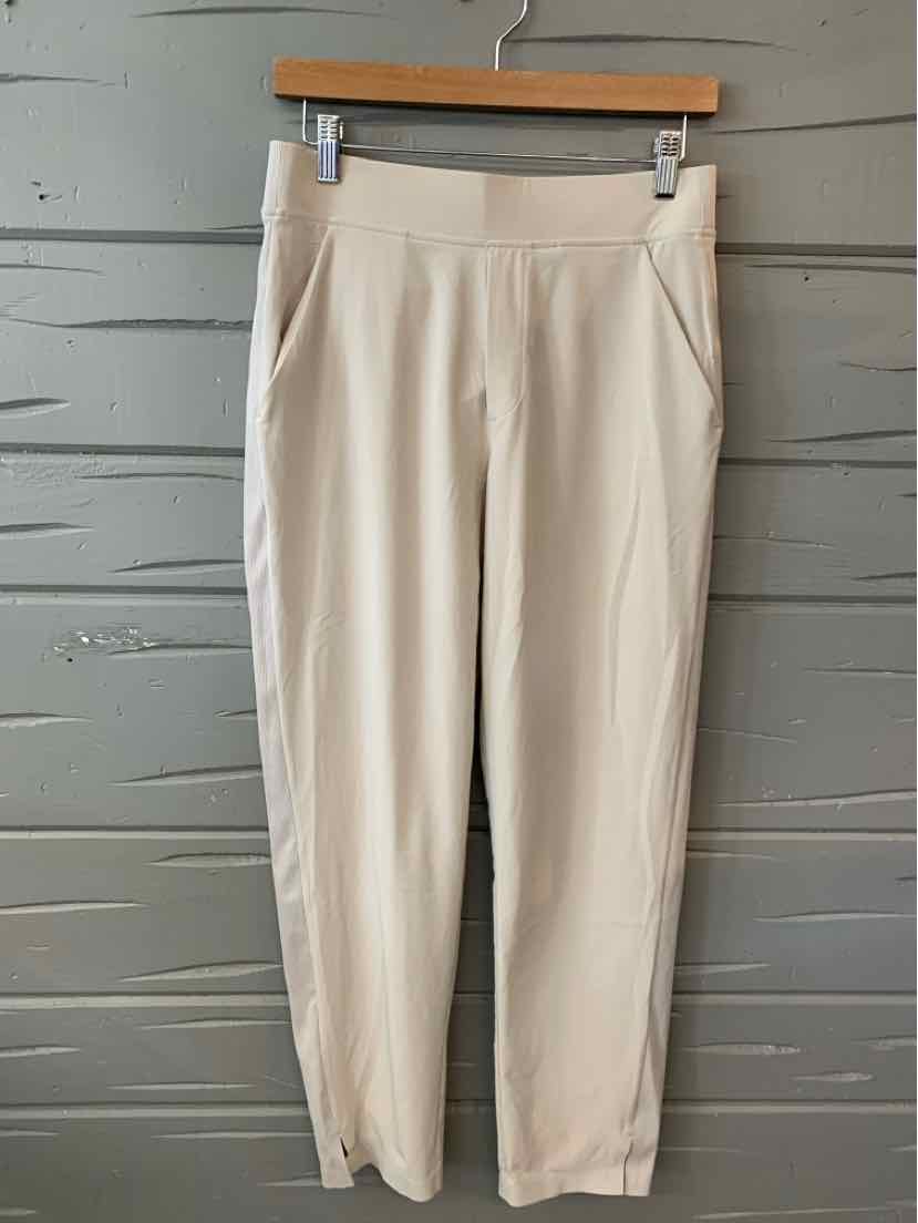 Tan high-waisted athletic pants with a slim fit and side pockets, size 6.