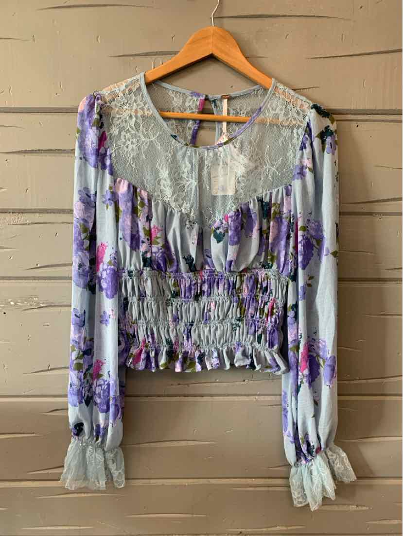 Long-sleeve floral blouse with lavender and purple flowers, lace yoke, smocked waist, and ruched cuffs.