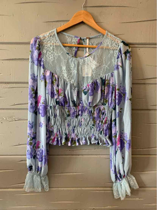 Long-sleeve floral blouse with lavender and purple flowers, lace yoke, smocked waist, and ruched cuffs.