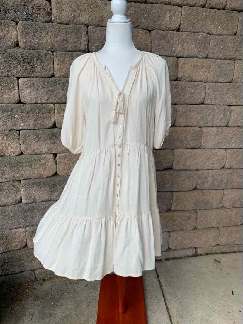 Cream-colored knee-length dress with puff sleeves, button front, and gathered hem detail.