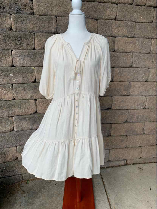 Cream-colored knee-length dress with puff sleeves, button front, and gathered hem detail.
