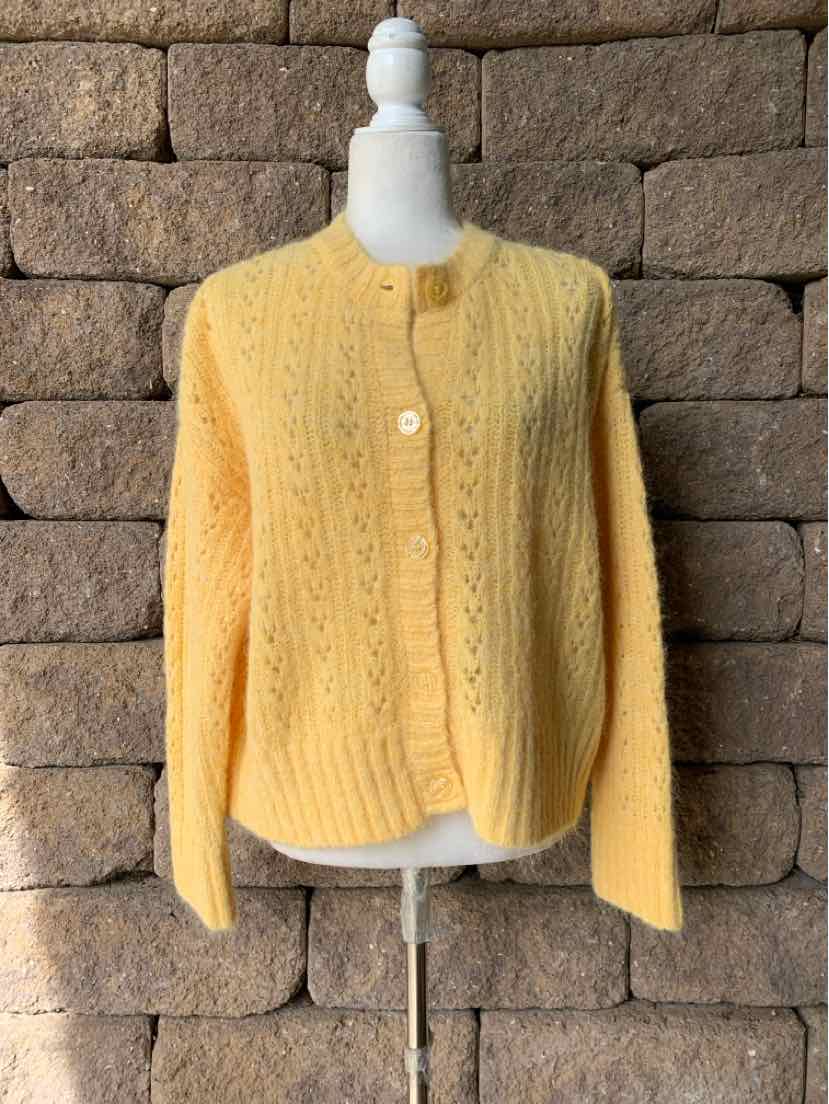Mustard yellow knit cardigan with cable-knit panels, long sleeves, round neckline, and white buttons.