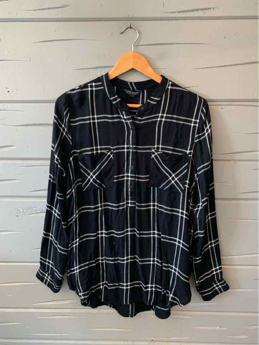 Black and white plaid long-sleeve shirt with button front and two chest pockets on wooden hanger.