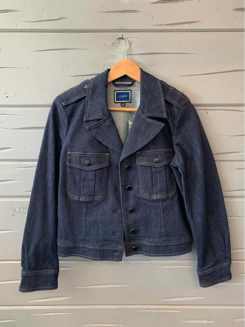 Navy blue denim jacket with button front and two chest flap pockets on wooden hanger.