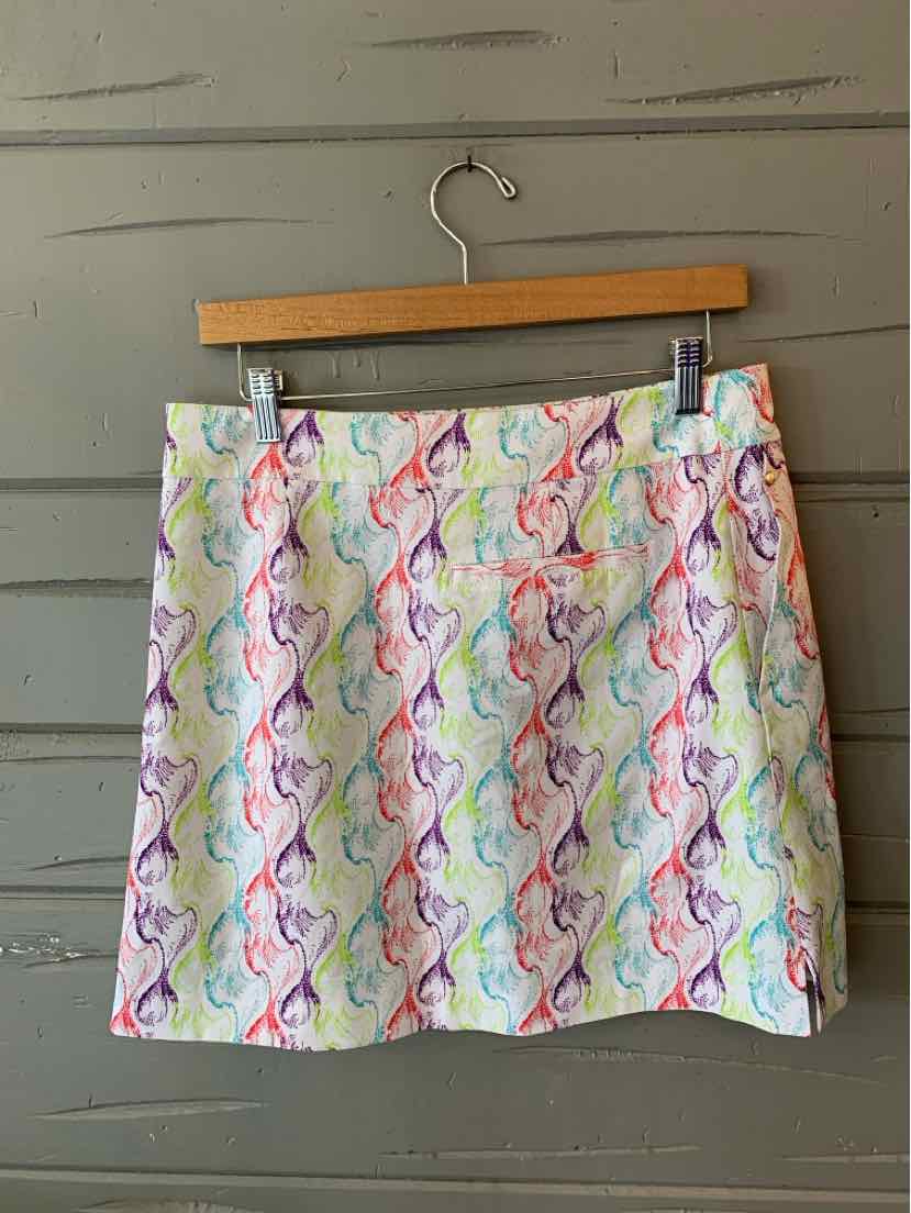 White skirt with colorful abstract wavy patterns and side pockets hanging on wooden hanger.