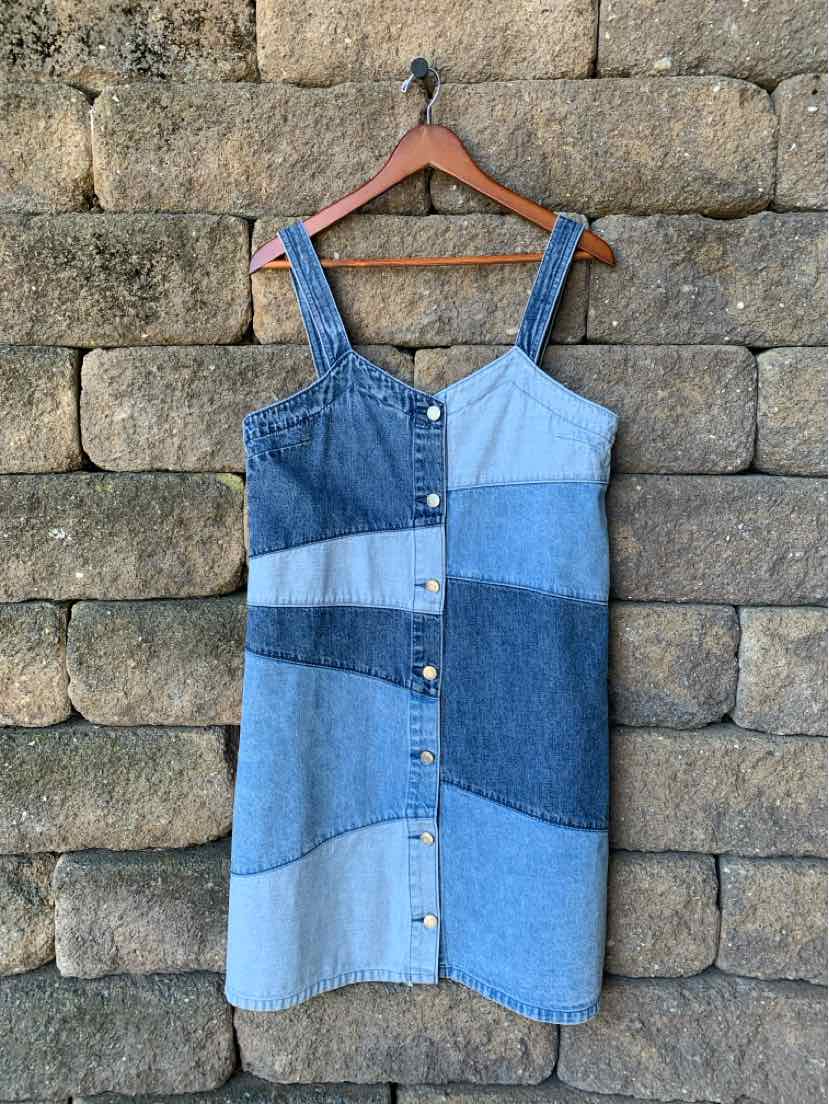 Women’s sleeveless patchwork denim dress in varying blue shades with front buttons and square neckline.