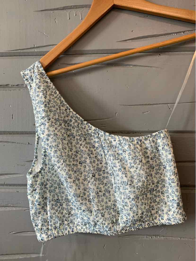 Blue and white floral print cropped tank top with wide straps on wooden hanger.