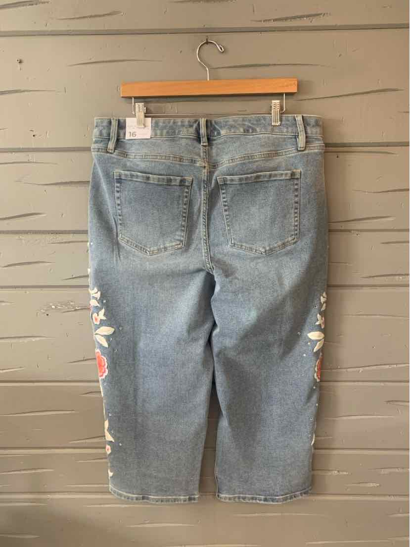 Light blue denim capri pants with floral embroidery along the outer legs, back pockets, and belt loops.