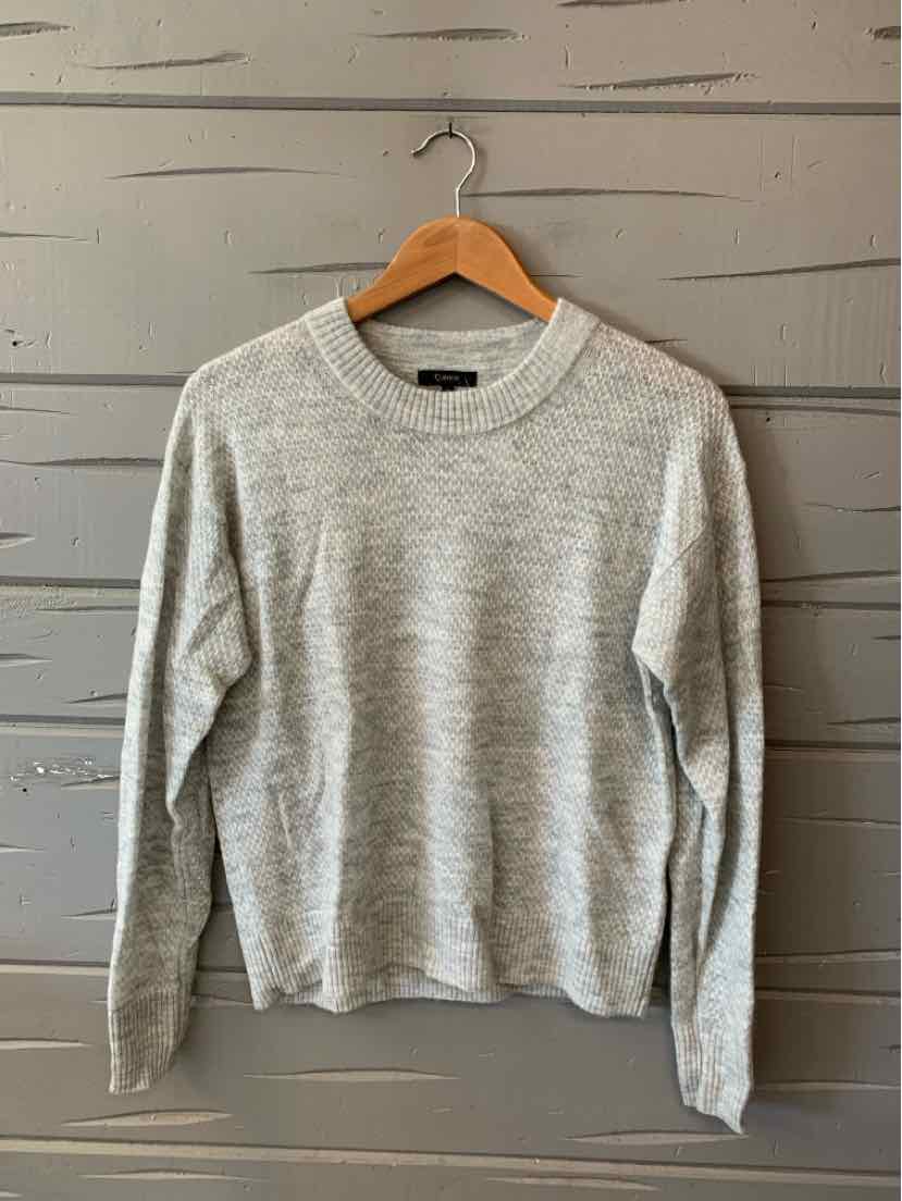 Light gray long-sleeve crewneck sweater with a soft knit texture hanging on wooden hanger.