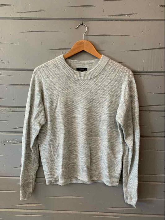Light gray long-sleeve crewneck sweater with a soft knit texture hanging on wooden hanger.