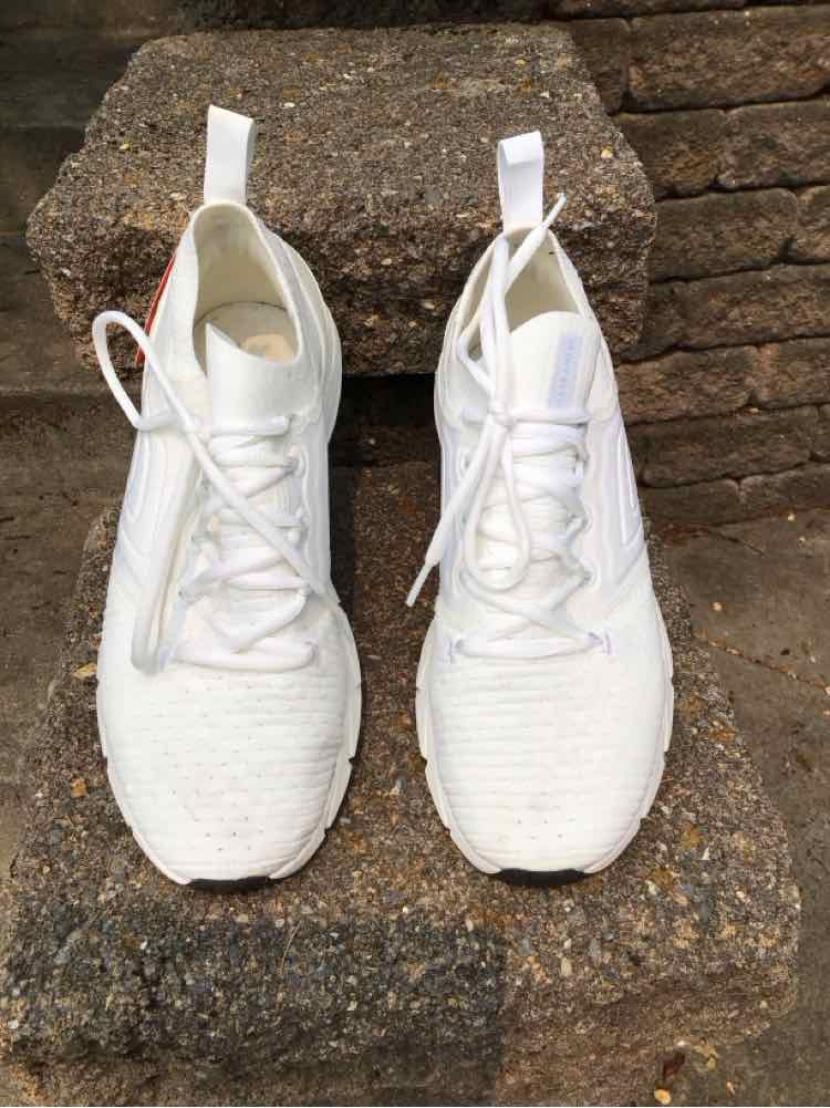 White Under Armour sneakers with mesh upper, lace-up design, and pull tabs on heel and tongue.
