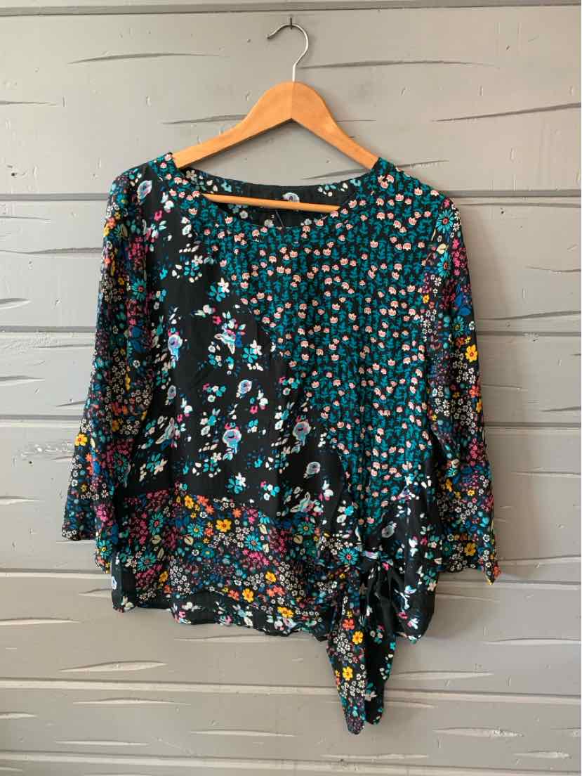 Long-sleeve blouse with mixed floral patterns in teal, black, and multicolor, featuring asymmetrical hem and lightweight.